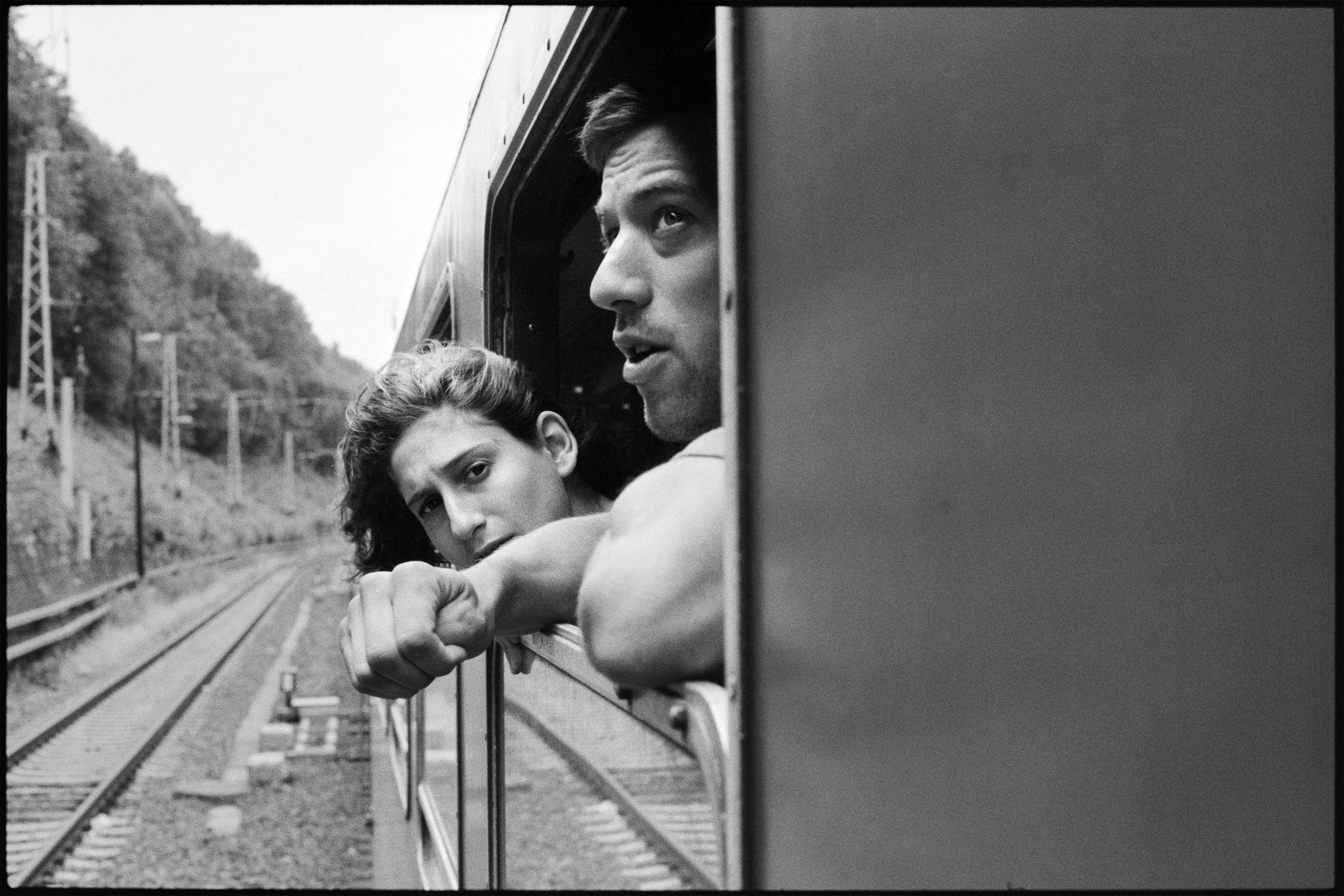 Une femme et un homme dans un train, les visages au vent.