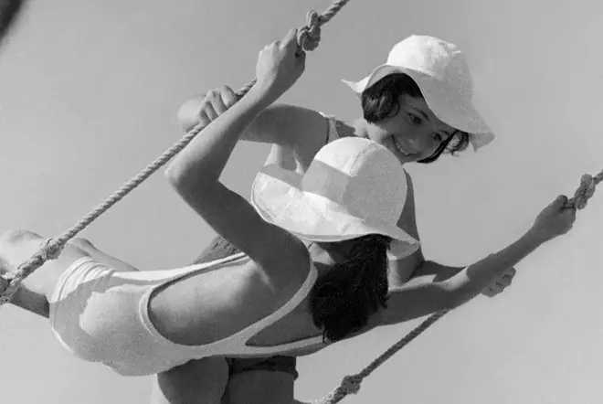 Two girls in swimsuits on a swing