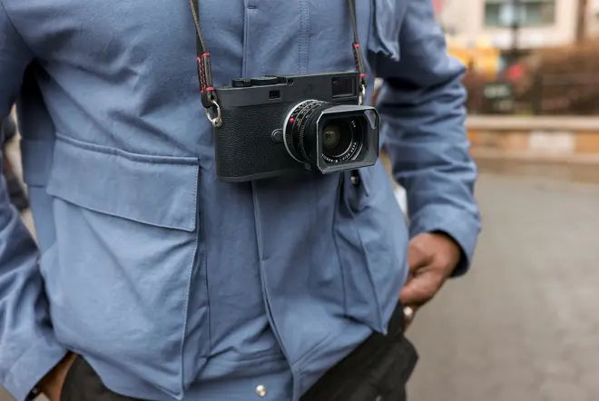 A person is standing with a camera around their neck.