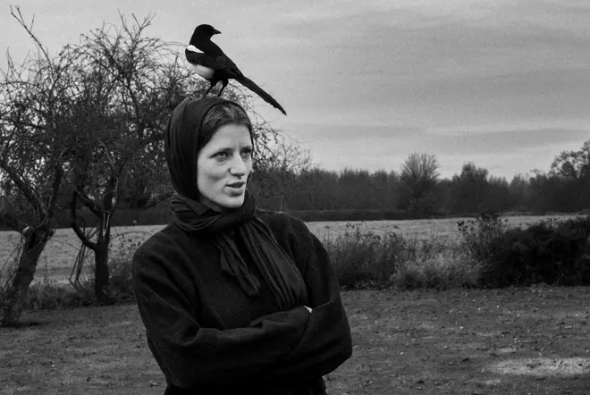 Black and white photo of a lady with a magpie bird on her head