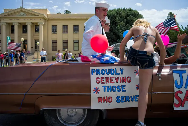 Woman gets into a convertible with sailors in America