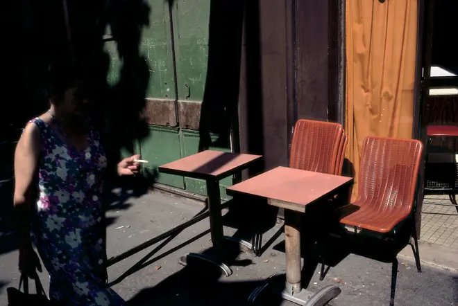 Femme dans l'ombre cigarette à la main à coté de chaises dans la rue