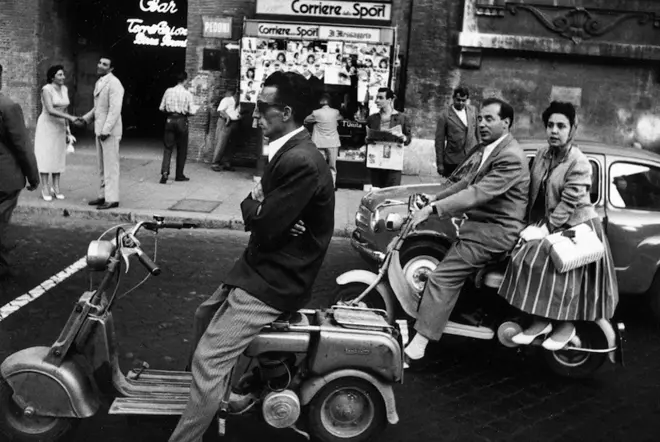 Black and White of a crossing in Rome with people on vespa waiting for traffic light to change.