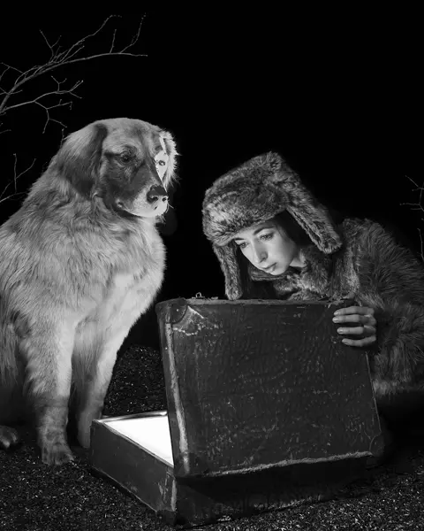 Viktoria Sorochinski and a dog looking into an old suitcase that is glowing inside. 