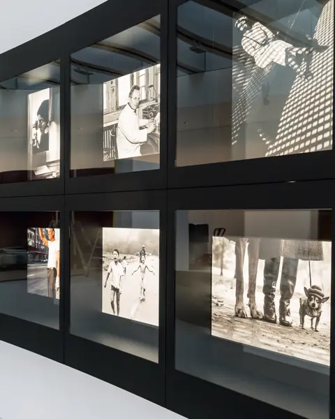 An exhibition of black and white photographs of famous events, presented in two curved rows.