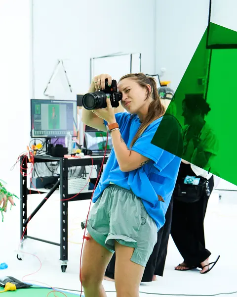 Photographer takes a picture in a studio of a model in a green net outfit.