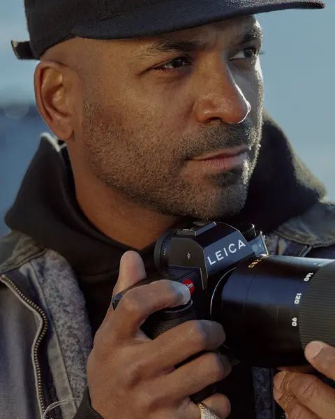 Close-up of a man holding a camera with skyscrapers in the background. 