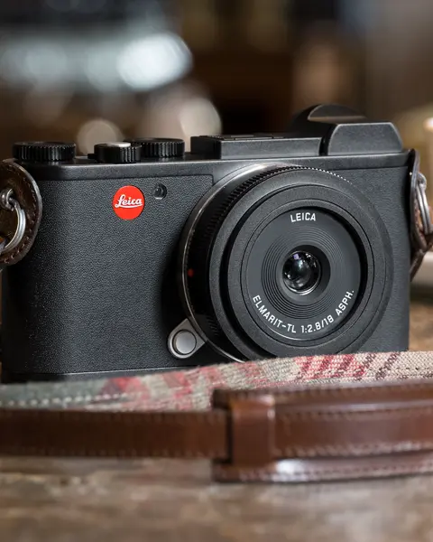 Leica camera on wooden counter with coffee cup in background