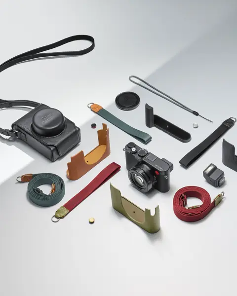 Camera with various accessories, such as straps and protective covers, on a light background