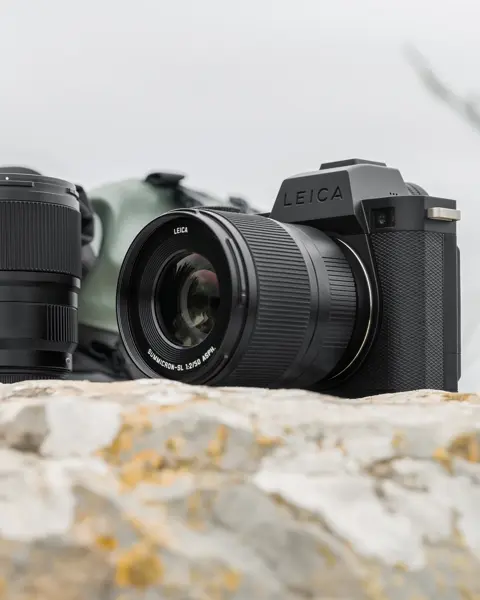 Leica cameras placed on a light-colored rock or stone with the sky in the background