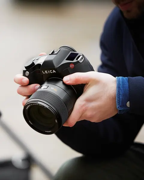 Close-up of a man holding a Leica camera in his hands
