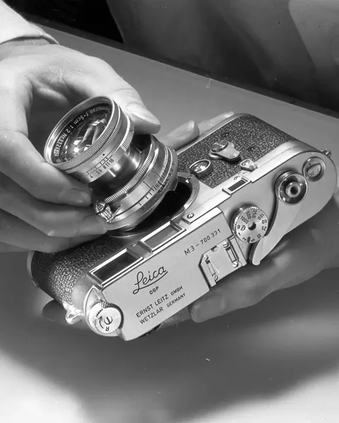 Man mounts lens on Leica M3