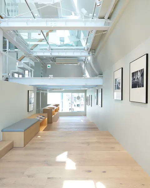 Bright, modern room with stairs, wooden floor and framed black and white photos.