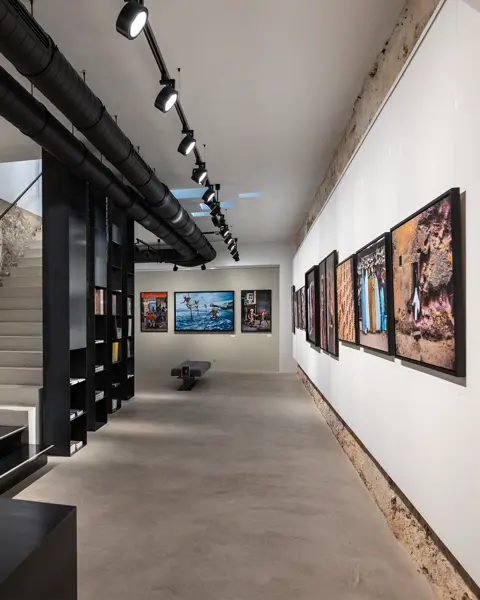 Exhibition room with photographs on the wall and a staircase leading upstairs.