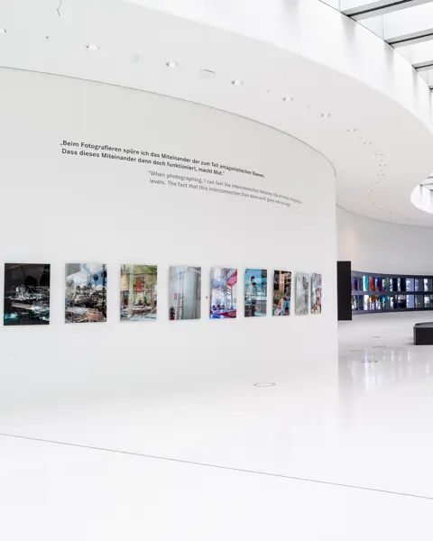 Bright, modern exhibition space with photographs on a white, curved wall.