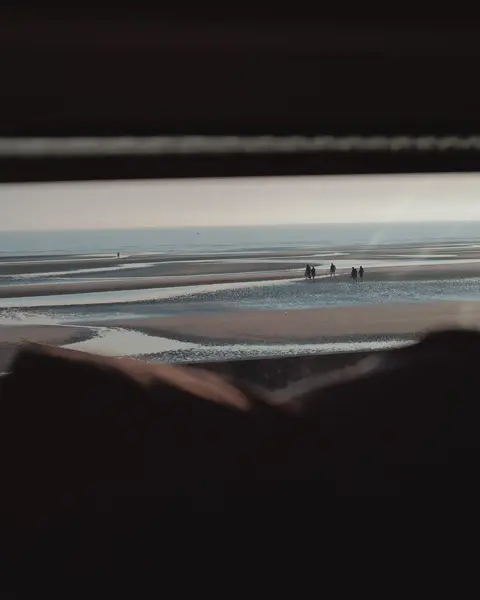 People on the beach photographed from a small window of a caravan