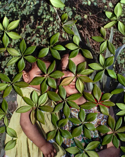 woman with her child behind leafs