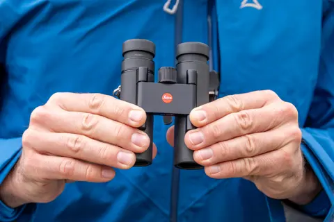 Man is holding his Leica Noctivid Compact