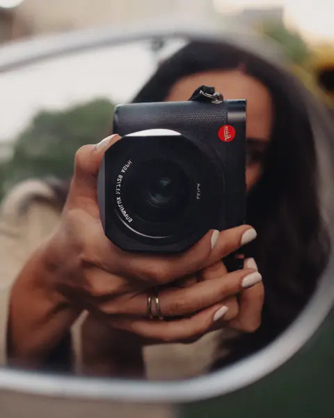 Woman taking a picture with the Leica Q into a side mirror
