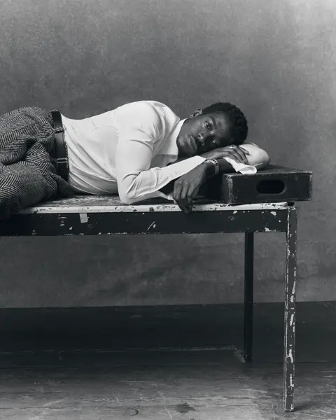 Portrait en noir et blanc de l'acteur Damson Idris allongé sur une table