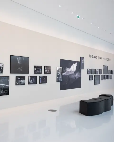Bright, modern exhibition space with photographs on a white wall.