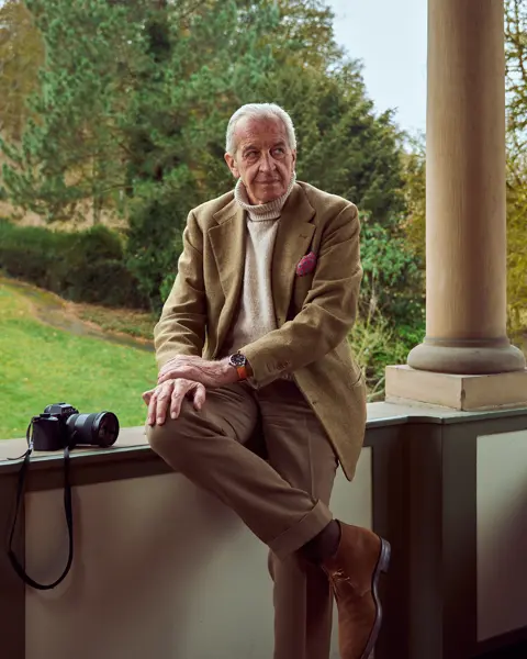 John Golberger is sitting on a veranda with a Leica beside him and a Leica ZM 12 on his wrist