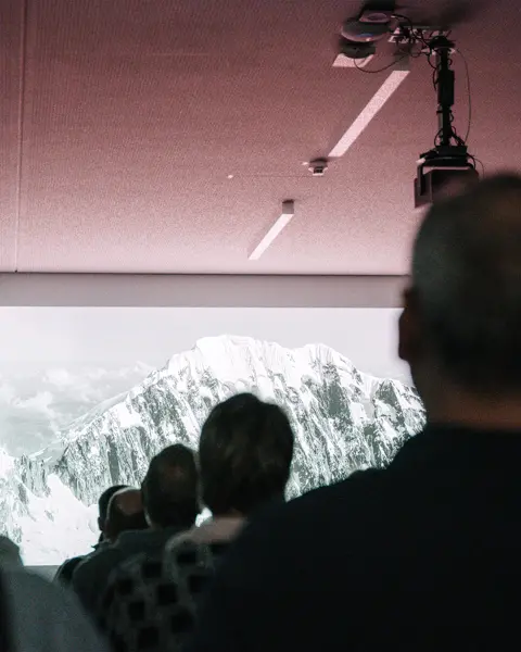 People are watching a presentation on a screen at a Leica event