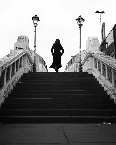 black-and-white photograph, woman running up a flight of stairs