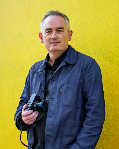 Jesse Marlow with a Leica M EV1 in front of a yellow wall