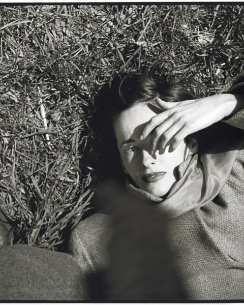 Frau liegt im im Gras und hält sich Hand ins Gesicht, Saul Leiter