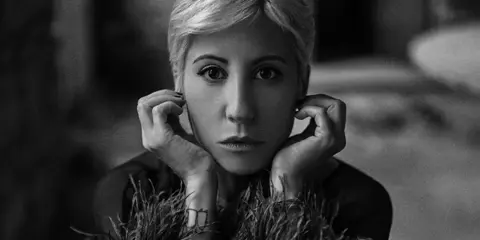 Black-and-white portrait of a person gazing directly into the camera.