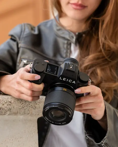 Close-up of a photographer adjusting a Leica camera.