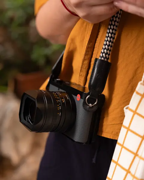 Person carrying a Leica camera while exploring outdoors