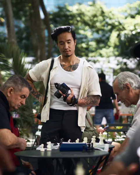 Documentary photograph of photographer Billy Dinh observing a chess game in a New York City park with a Leica Q, capturing everyday street photography and urban life.