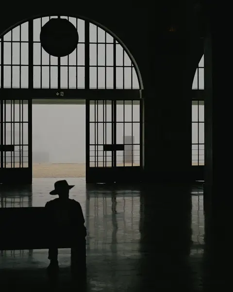 Ombre d'un homme assis dans une gare avec un chapeau