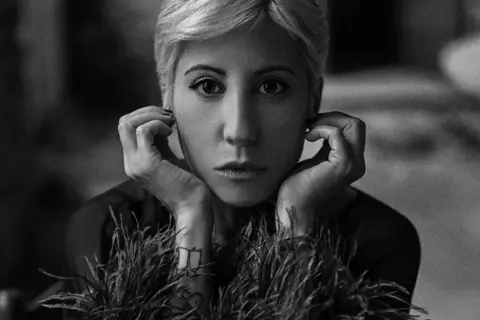 Black-and-white portrait of a person gazing directly into the camera.