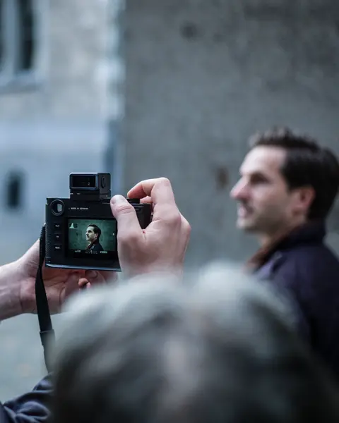 A photographer captures a portrait with a Leica camera during an outdoor photography workshop.