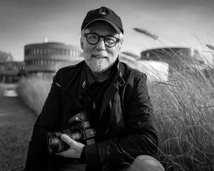 Portrait of photographer Ragnar Axelsson holding a Leica camera