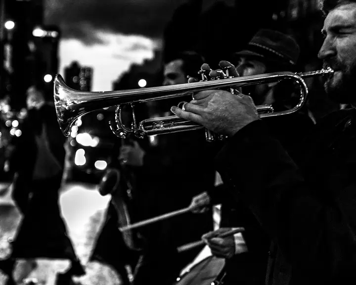 Several musicians and a trumpeter in the foreground play music in the street