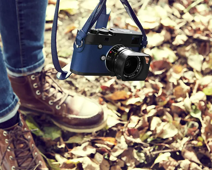 Man in the fall leaves with blue leica camera