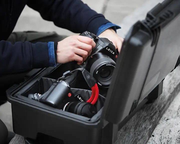 Close-up of a person taking a Leica camera out of a camera case