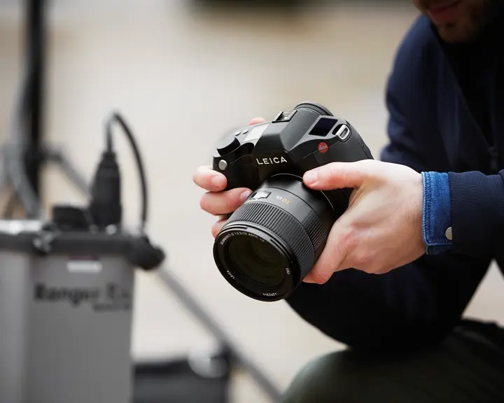 Close-up of a man holding a Leica camera in his hands