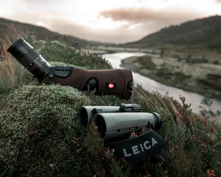 Leica-binoculars-Noctivid-8x42-and-spotting-scope-lying-in-a-meadow-in-the-Scottish-Highlands