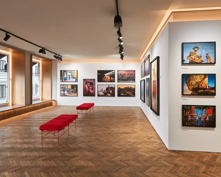 Exhibition space with red benches and photographs of people and places from all over the world.