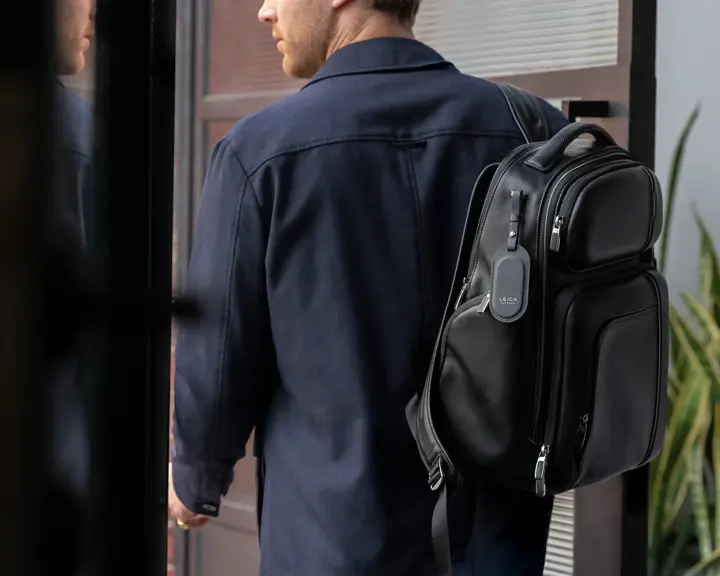 Man wearing a suit with a rucksack and a Leica leather tag
