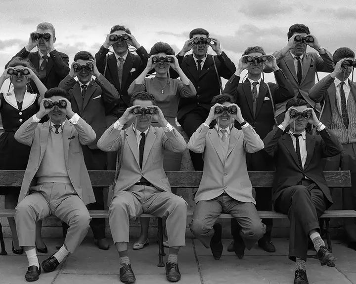 Women and men in 1960 with binoculars in front of their faces