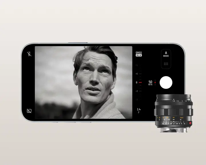 An iPhone displays an image with a man. In front of the phone is a Leica lense.
