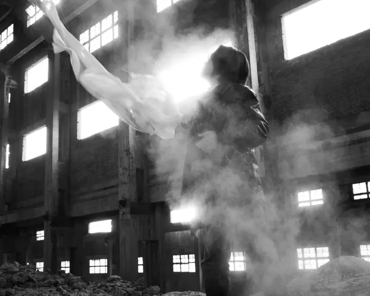 Black-and-white photograph of a man holding a white cloth in an empty old building