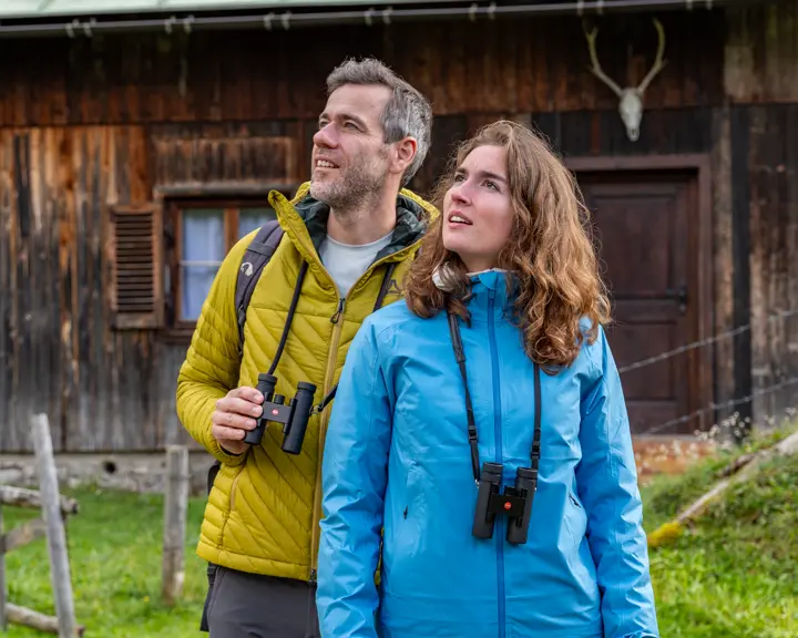 Two hikers in the mountains with their Leica Noctivid Compact