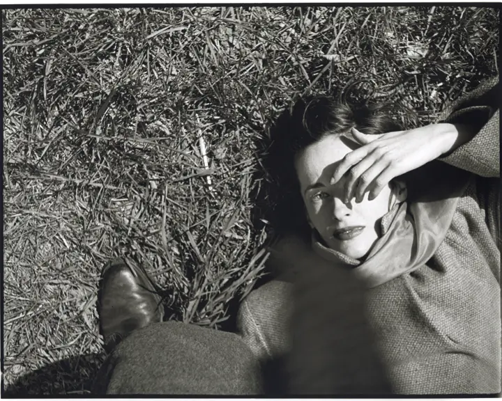 Frau liegt im im Gras und hält sich Hand ins Gesicht, Saul Leiter